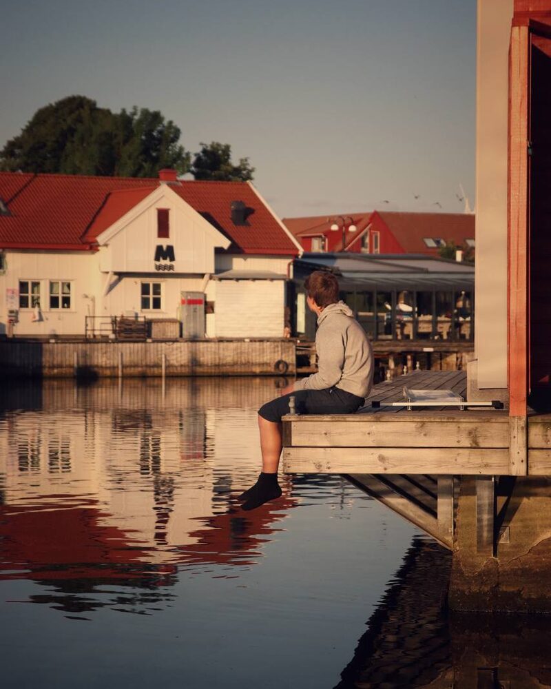 Person som sitter på en brygge i varmt kveldslys